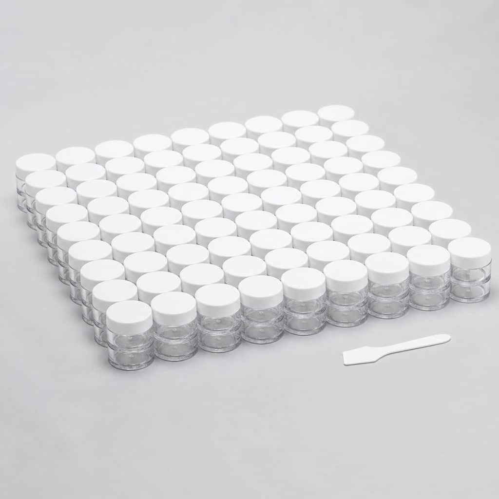 Petits pots transparents avec couvercle et spatule sur fond clair